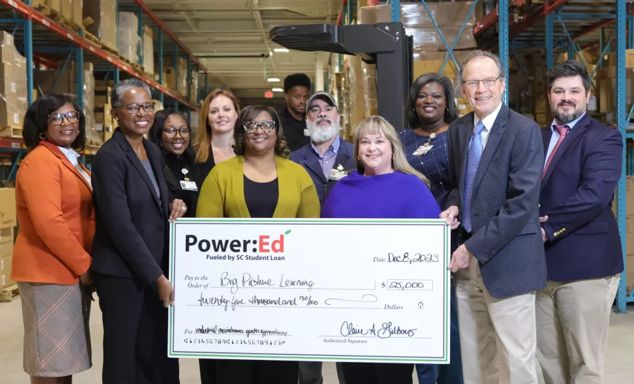 Executives pose with ceremonial check