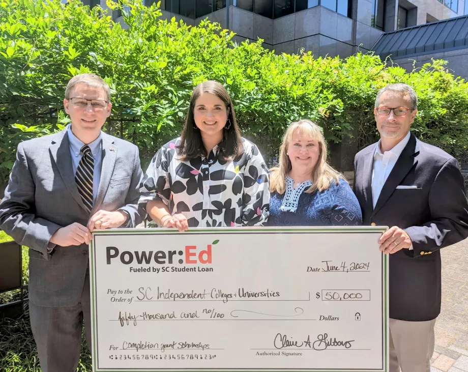 Executives pose with ceremonial check