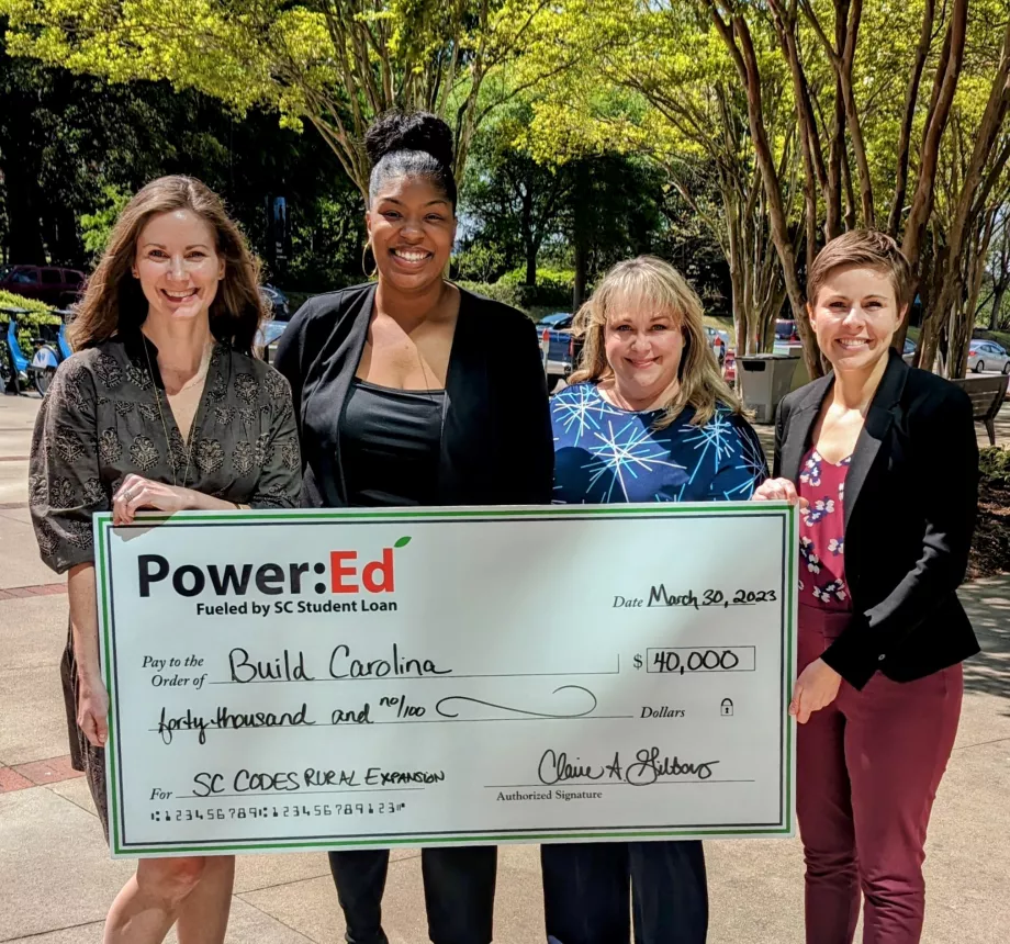 Women executives pose with ceremonial big check