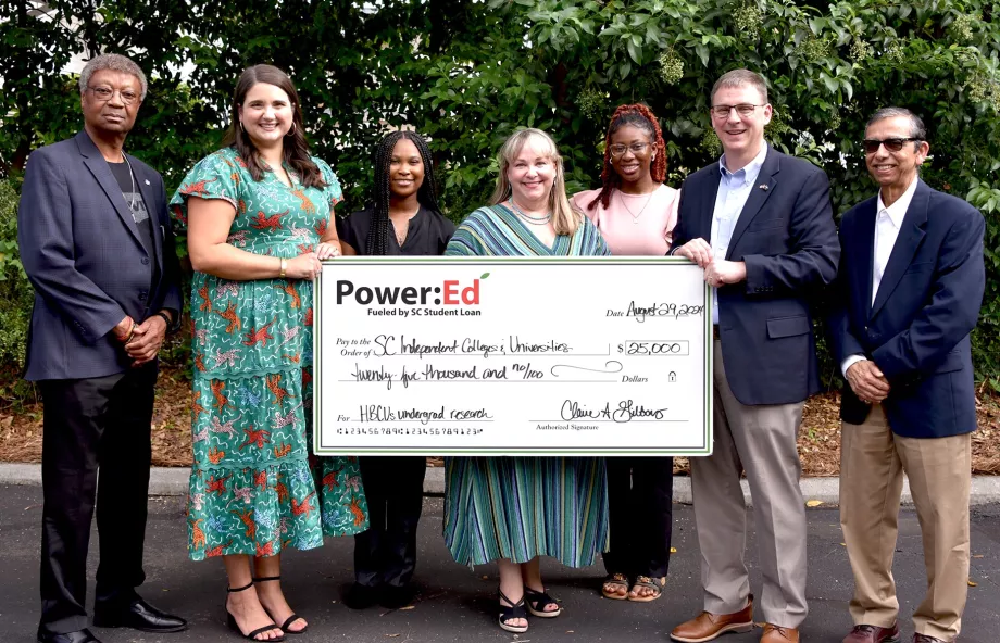 Executives and students pose with ceremonial check