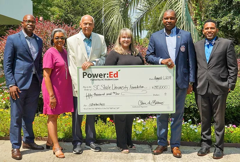 Executives pose with ceremonial check