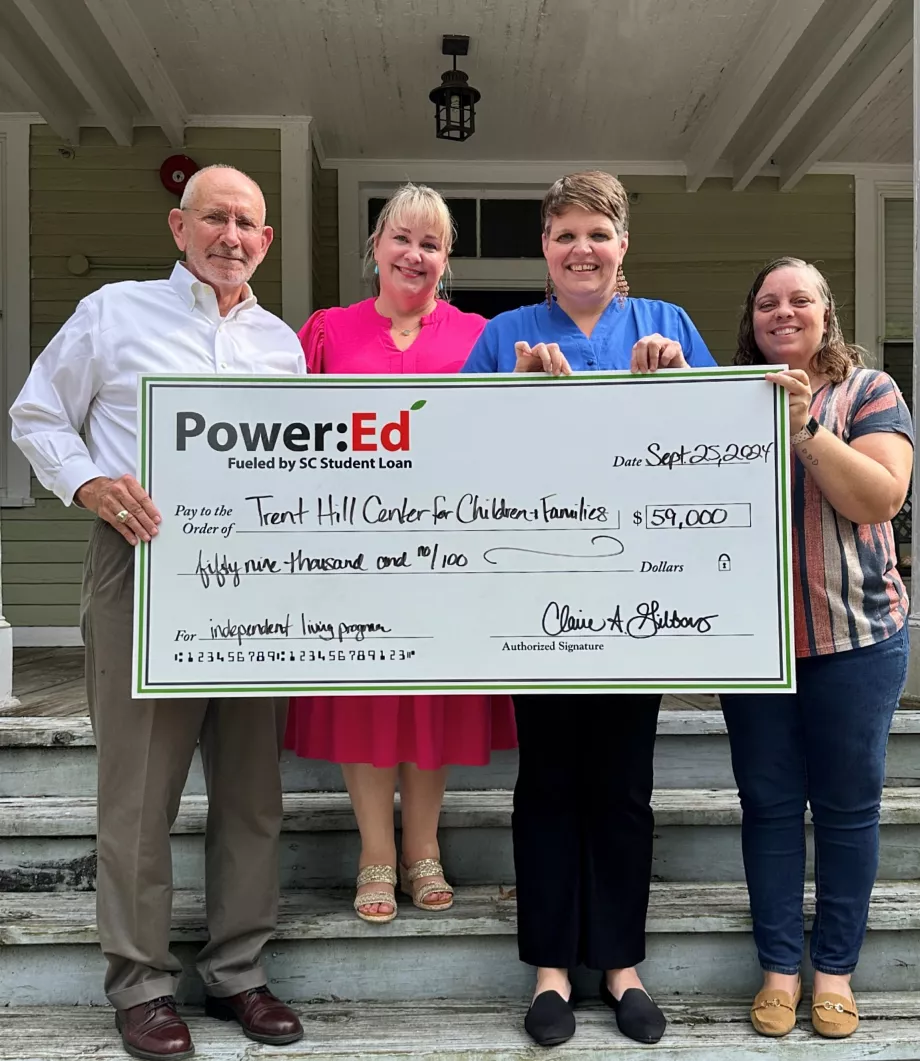 Executives pose with ceremonial check on house steps